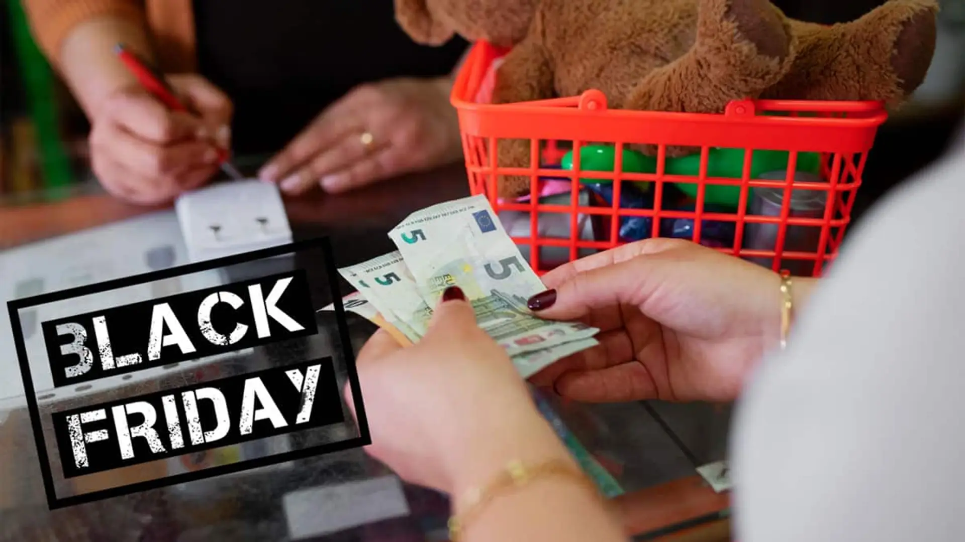 Cliente pagando en efectivo durante una compra de Black Friday con una cesta llena de juguetes en el mostrador.