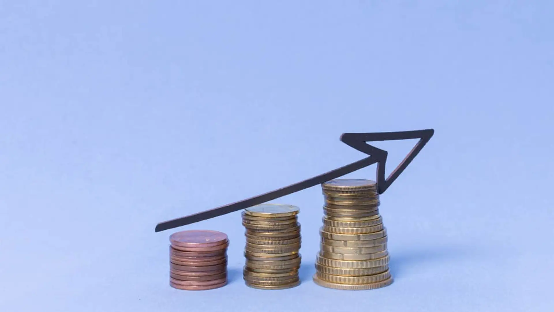 Pilas de monedas en crecimiento con una flecha ascendente, símbolo de inversión, ahorro y rentabilidad financiera.