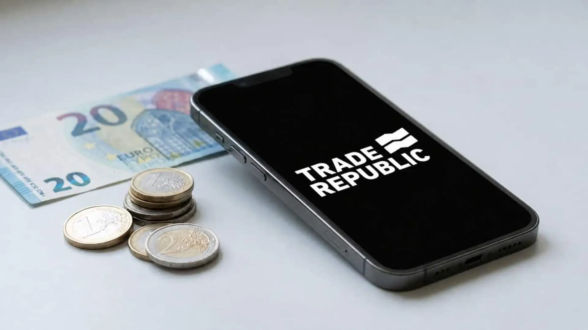Teléfono con la app de Trade Republic junto a billetes y monedas de euro sobre una mesa