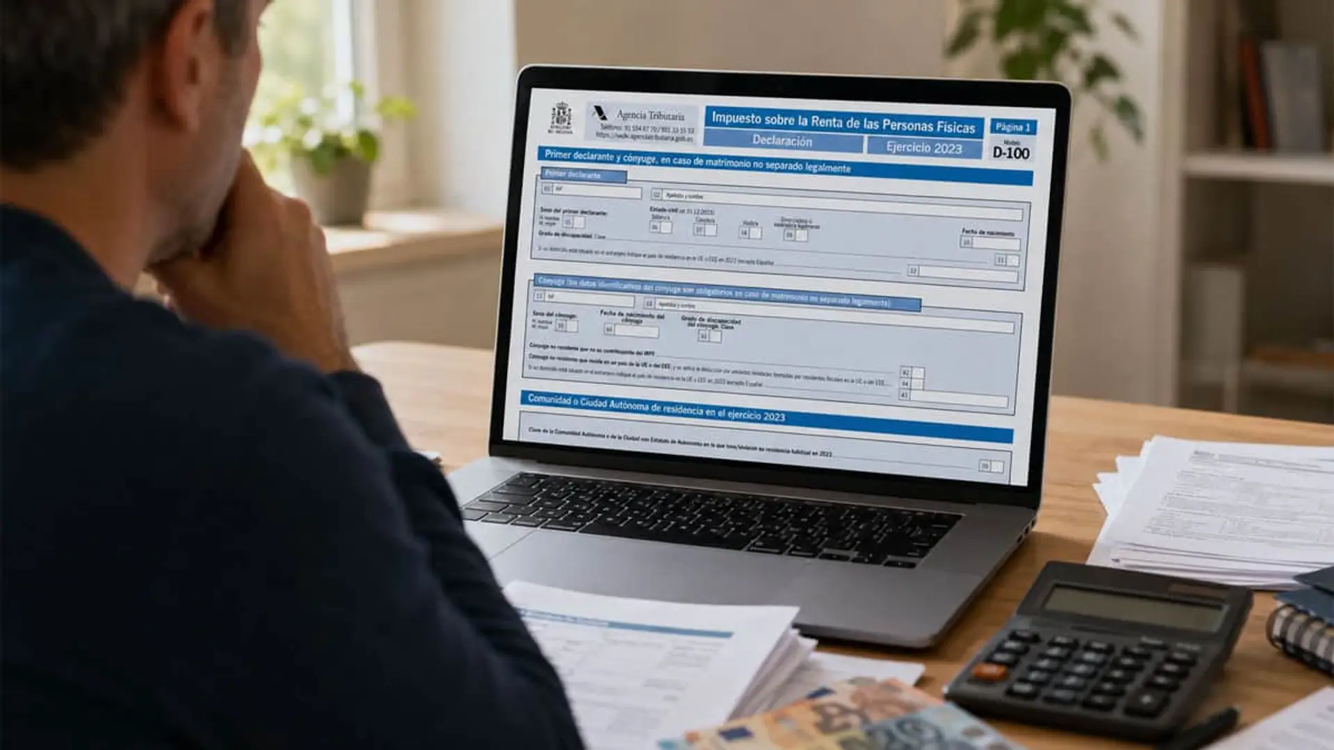 Hombre revisa la declaración de la renta en un portátil con calculadora y documentos fiscales