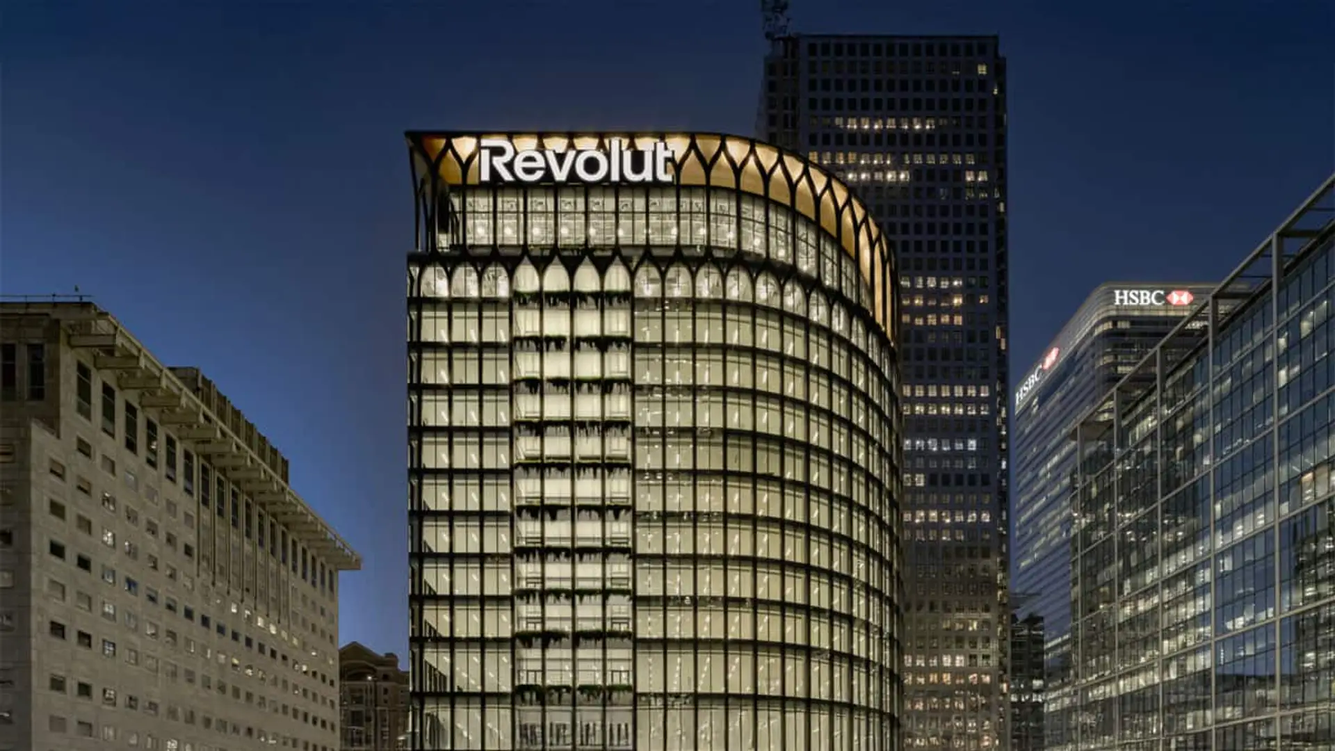Fachada del edificio principal de Revolut iluminado de noche en el distrito financiero de Londres.
