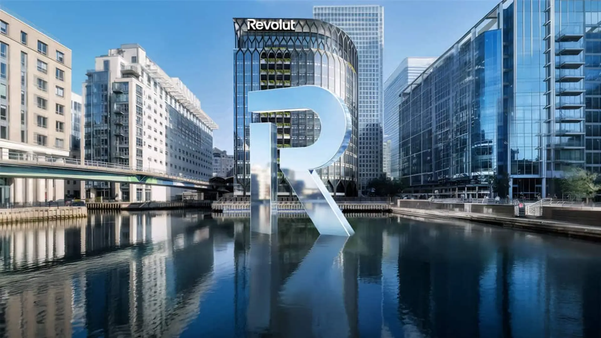Edificio corporativo de Revolut junto al agua con gran logo en una zona financiera urbana.
