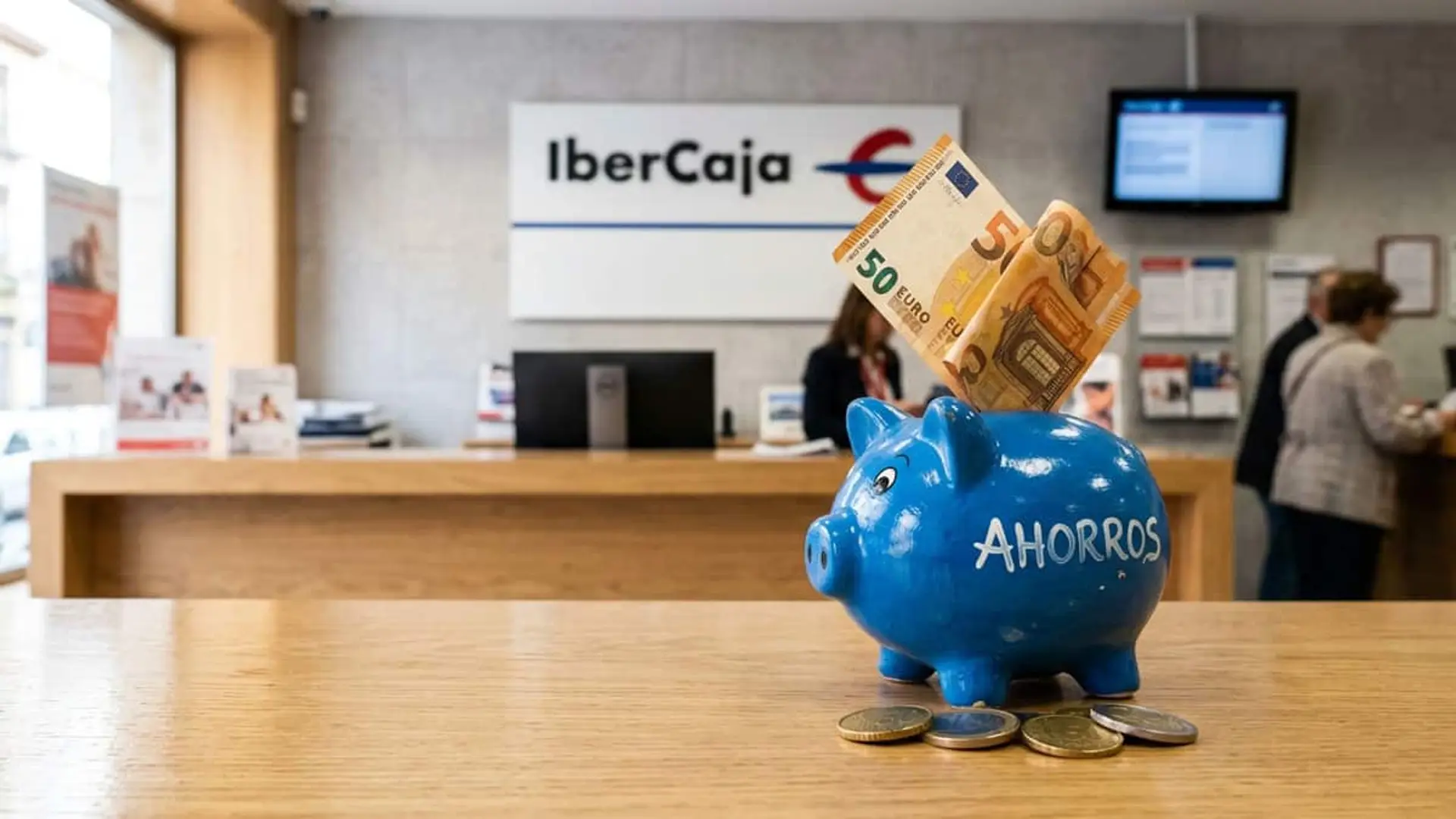 Ibercaja sube a 20.000 euros el saldo al 5% de la Cuenta Vamos: 1.000 euros el primer año Hucha azul con billetes y monedas en primer plano dentro de una oficina de Ibercaja