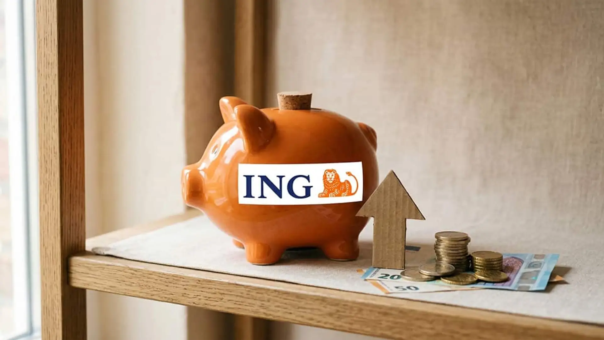Hucha de ING junto a euros y una flecha ascendente que representa el aumento de la rentabilidad del ahorro
