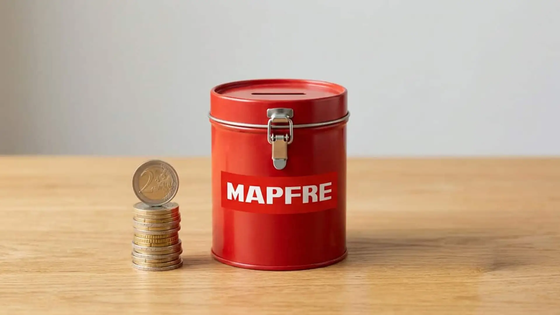 Millón Vida al 2,4%: por qué Mapfre dice que su seguro de ahorro supera la rentabilidad de las Letras del Tesoro Hucha roja de Mapfre junto a una pila de monedas sobre una mesa de madera