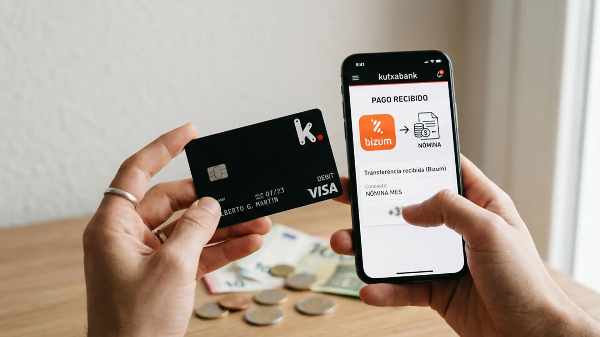 Móvil con la app de Kutxabank mostrando un pago recibido por Bizum junto a una tarjeta bancaria
