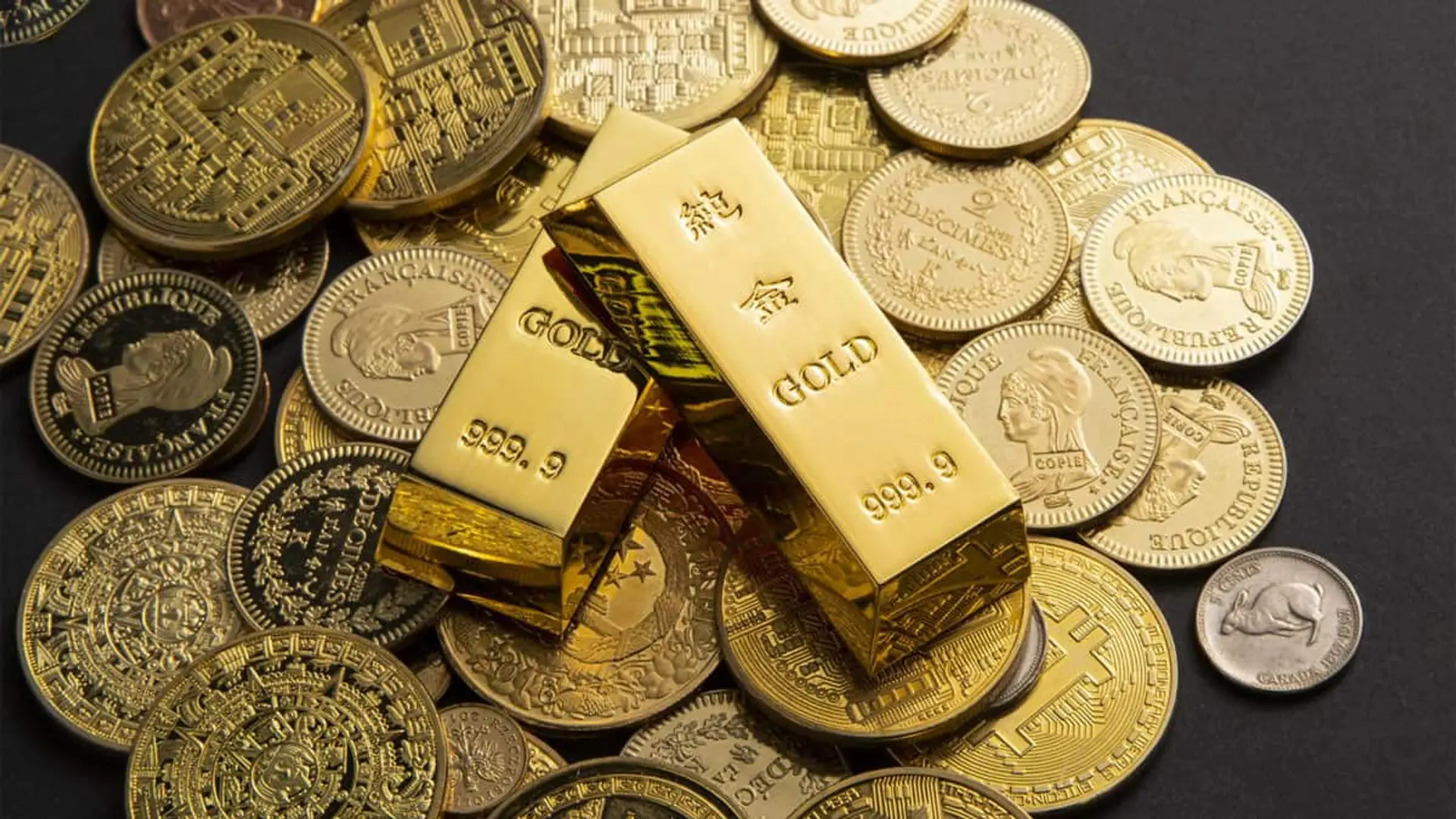 Ni oro ni IA: experto aconseja rotar la cartera hacia estos valores ante el riesgo de caídas Lingotes de oro rodeados de monedas doradas de distintos países.
