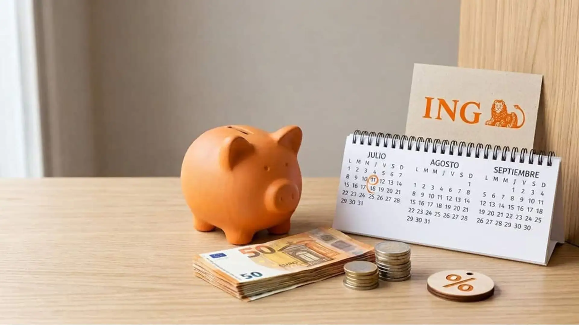 ING renueva su Depósito Bienvenida al 3% en 3 meses: sin importe mínimo, sin comisiones y hasta 50.000 euros Hucha naranja junto a un calendario de julio, agosto y septiembre, billetes, monedas y el logotipo de ING
