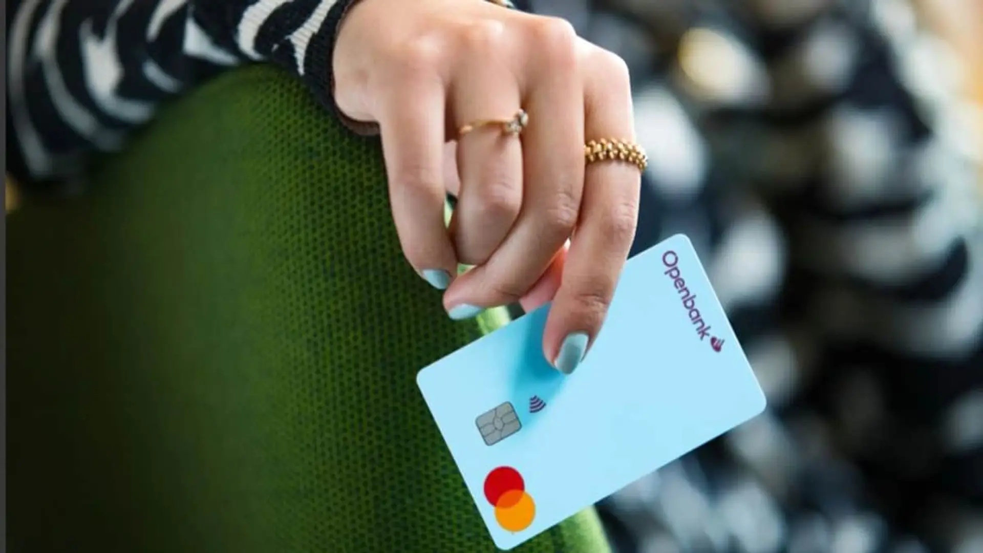 Openbank eleva al 3,04% TAE la rentabilidad de su cuenta para nuevos clientes Mano de una persona sosteniendo una tarjeta de crédito Openbank de color azul claro.