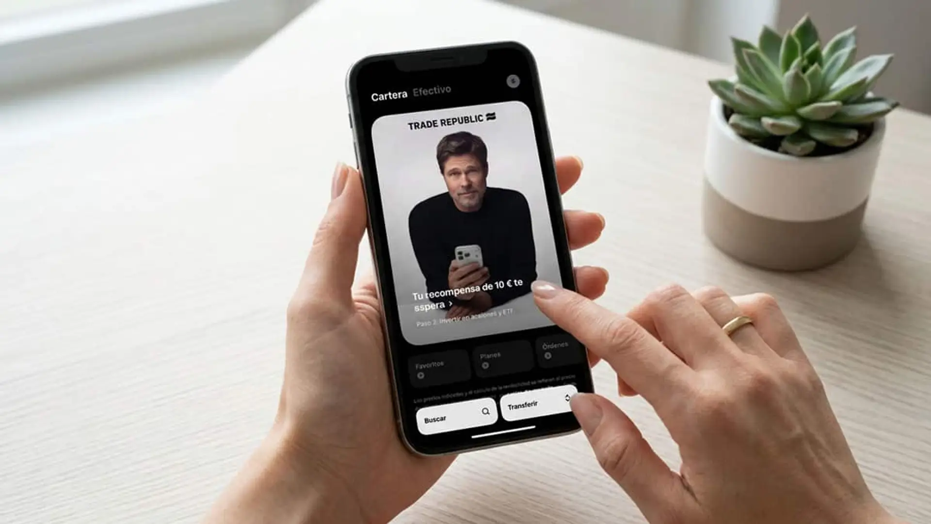 Manos usando la app de Trade Republic en un móvil sobre una mesa clara