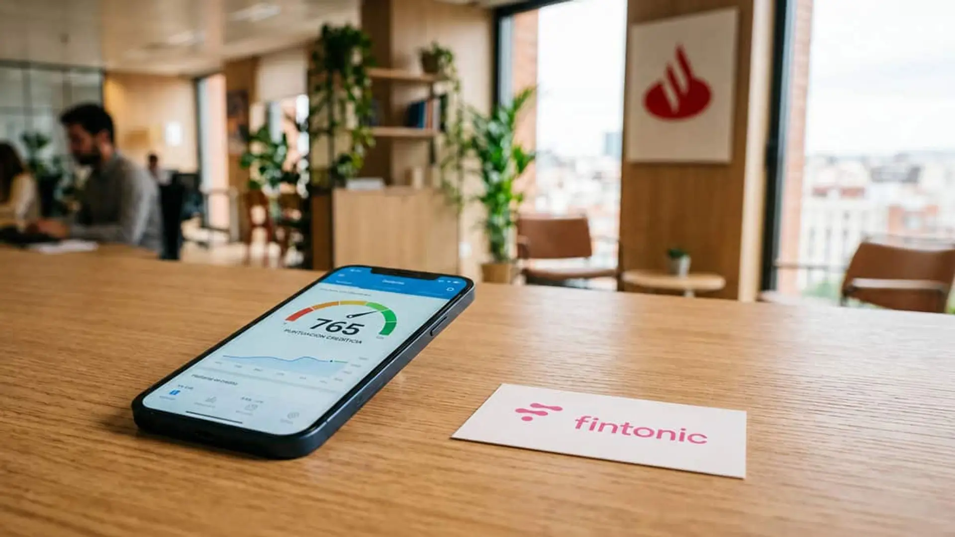 Fintonic tiene nuevo CEO y llega desde el Banco Santander: Eneko Fonseca sustituye a Armando Baquero Móvil con una puntuación crediticia junto al logo de Fintonic en una oficina con el logo de Santander al fondo