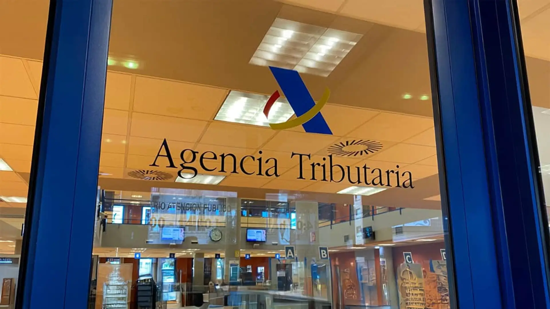 Logotipo de la Agencia Tributaria en la puerta de una oficina de atención al público.