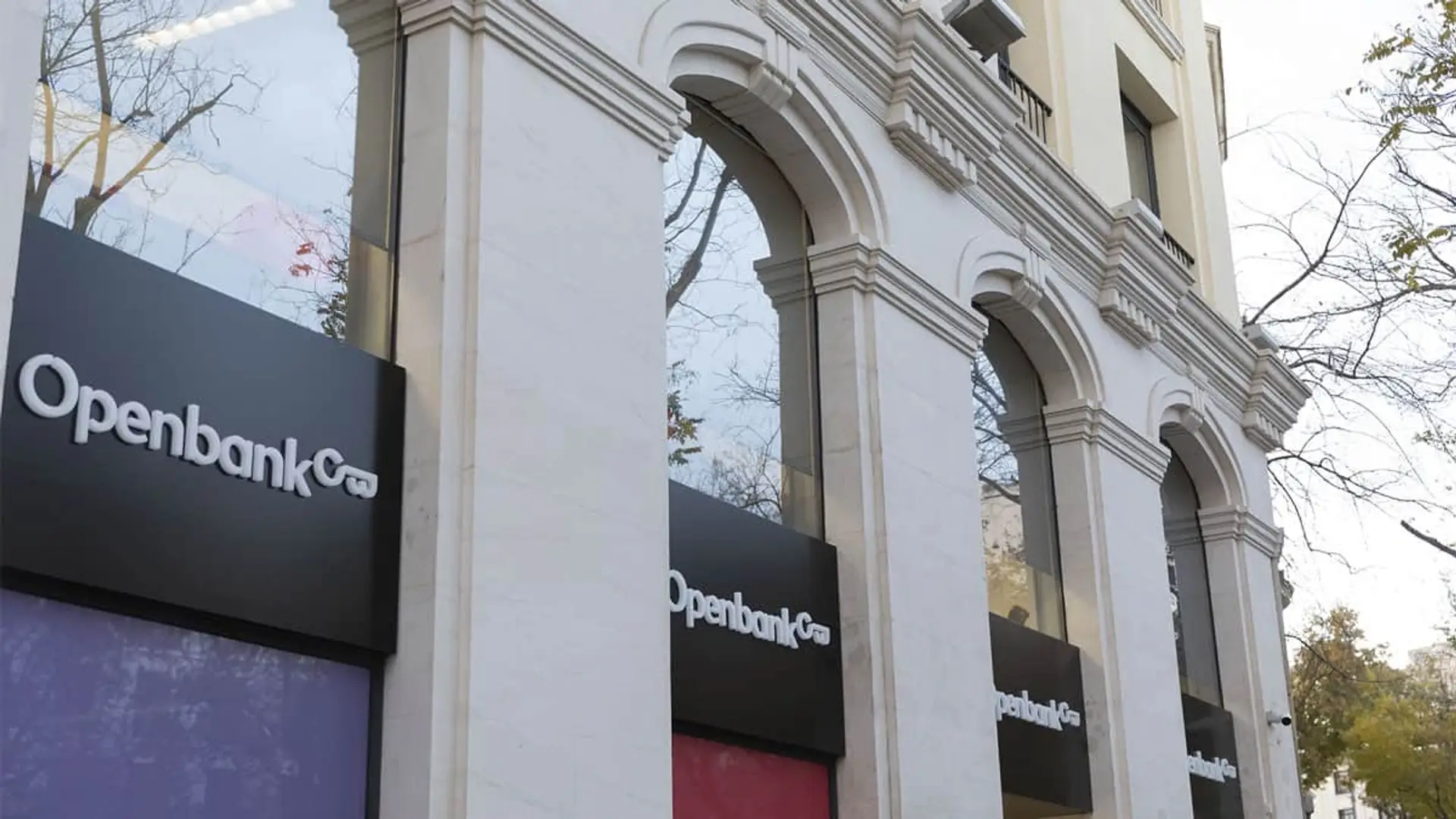 Fachada de una oficina de Openbank. Logotipos del banco digital en un edificio clásico con arcos de piedra blanca.