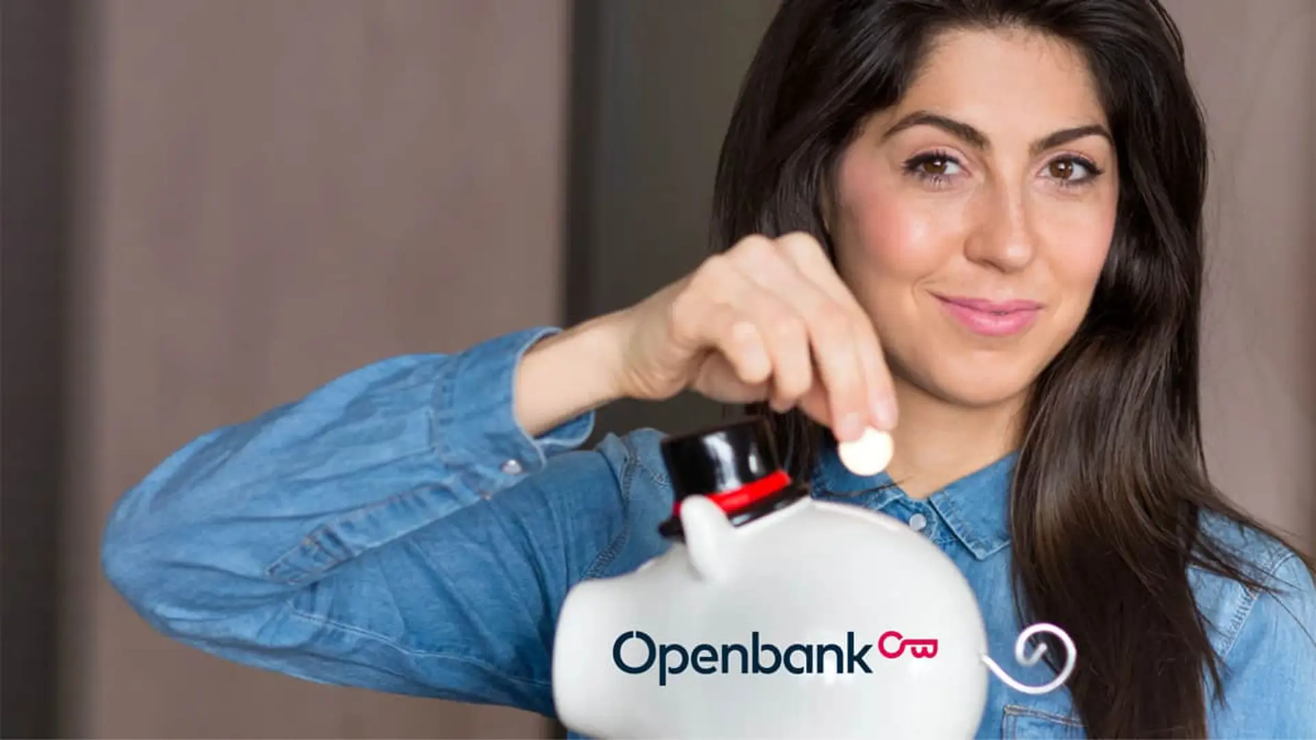 Mujer joven ahorrando dinero en hucha de cerdito con el logo de Openbank para el futuro.