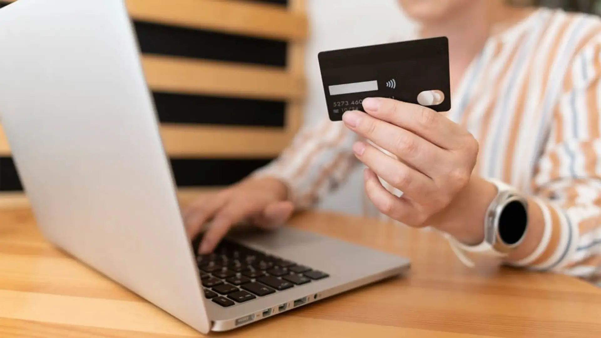 Persona realizando un pago online con tarjeta de crédito y ordenador portátil en una tienda virtual.