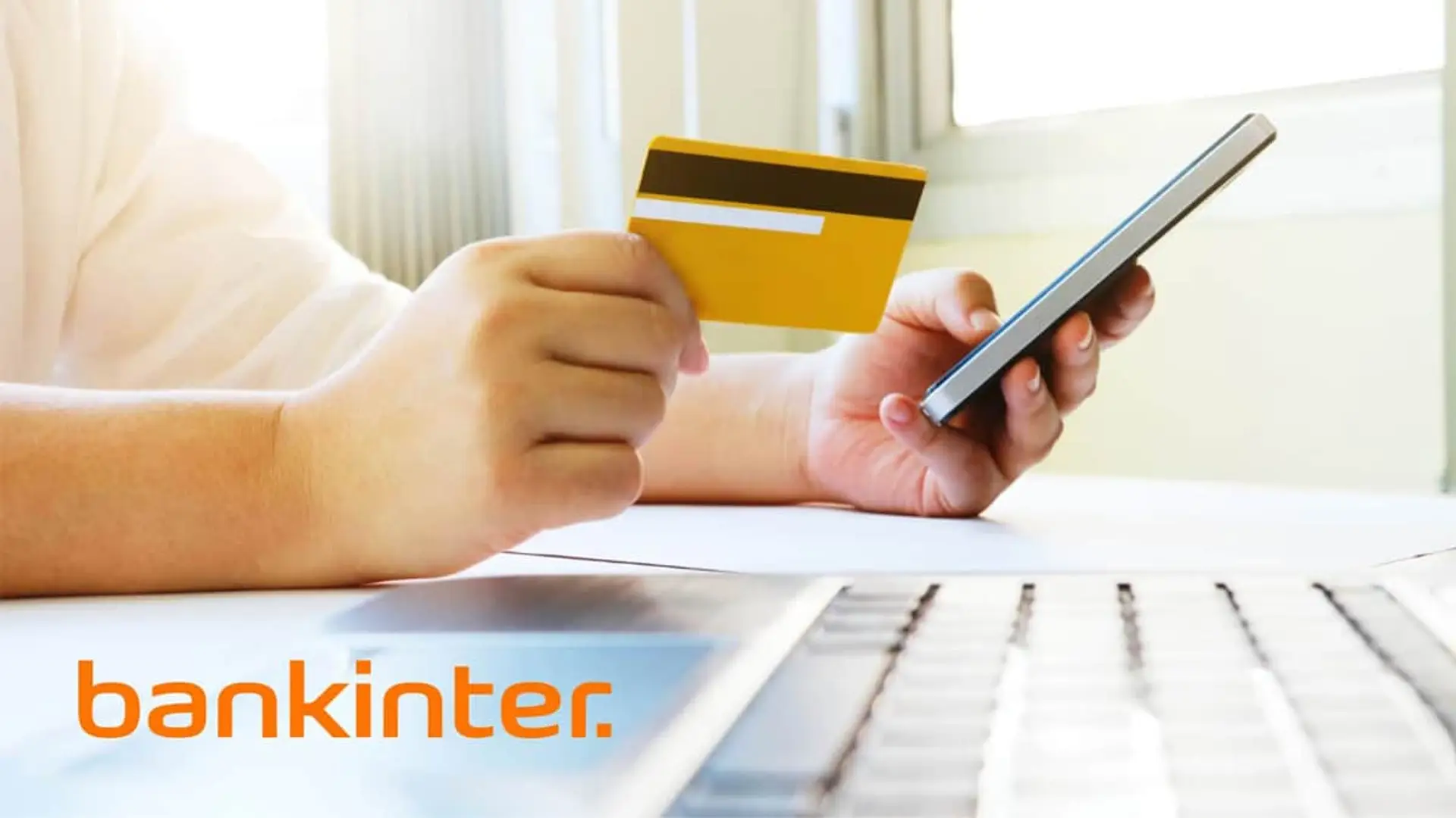 La cuenta remunerada de Bankinter que paga un 2% TAE sin condiciones tiene los días contados Usuario con tarjeta de Bankinter y smartphone frente a un ordenador realizando gestiones de banca digital.