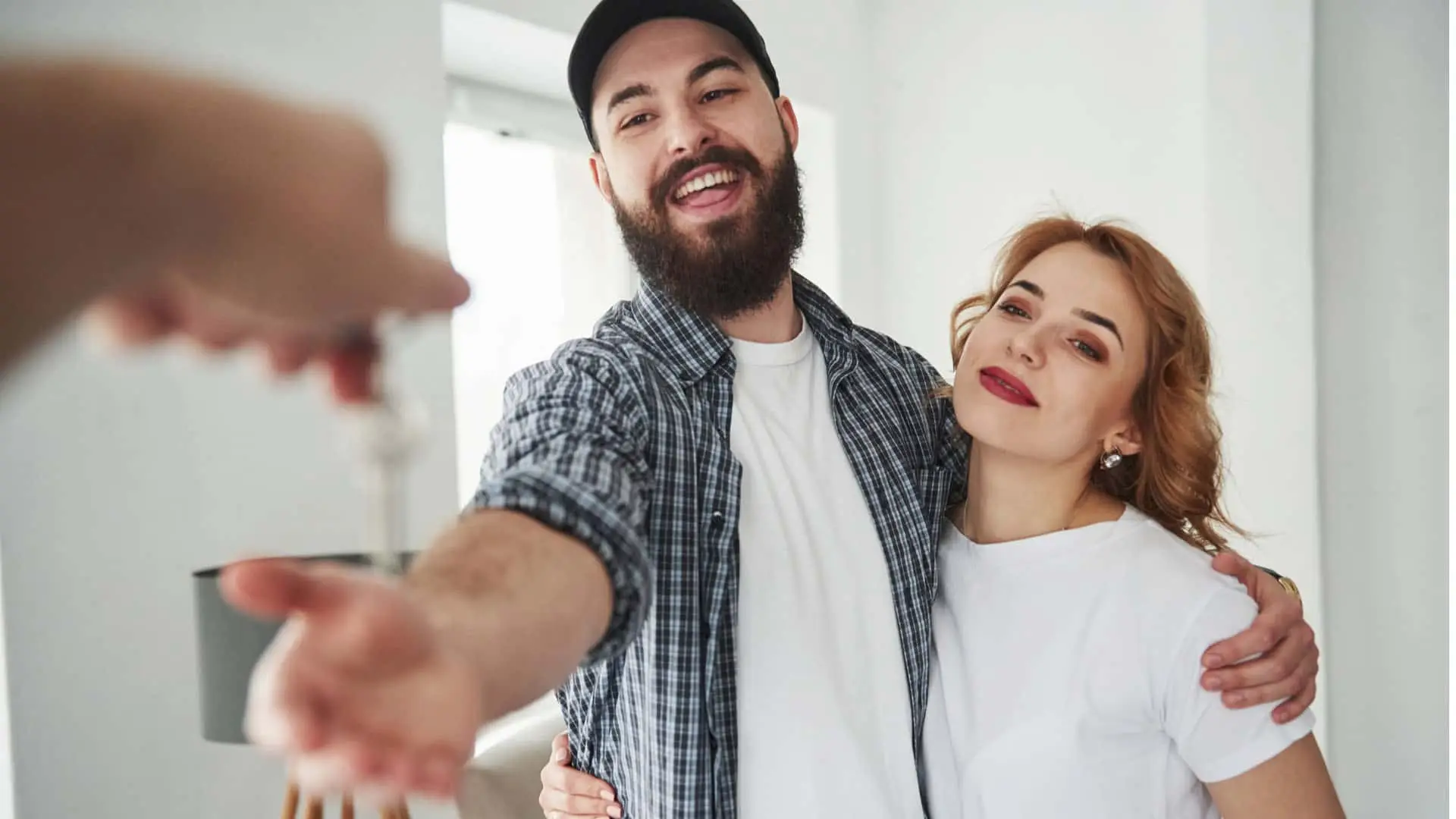 Pareja joven recibe las llaves de su nuevo piso o casa. Concepto de compra, alquiler o firma de una hipoteca con una inmobiliaria.