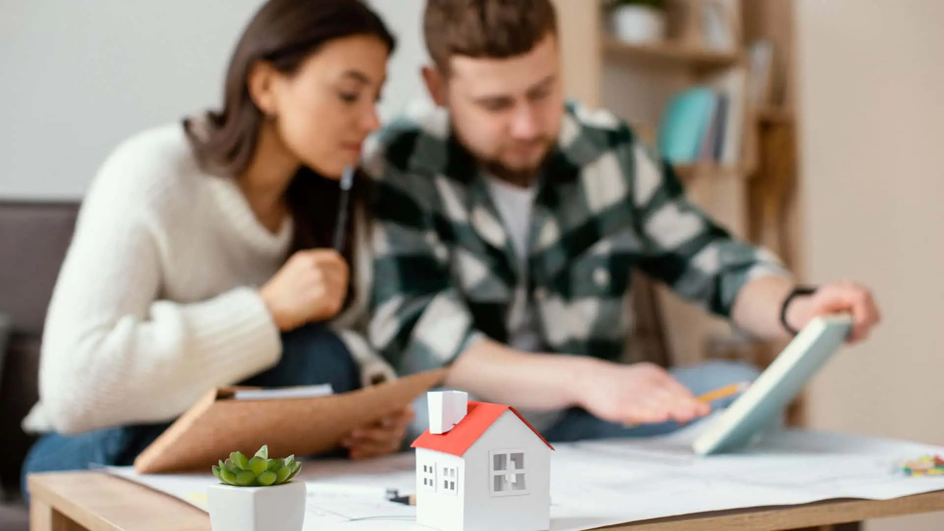 Pareja planificando la compra de su casa, revisando la hipoteca y el seguro de hogar. Ahorro para una primera vivienda.