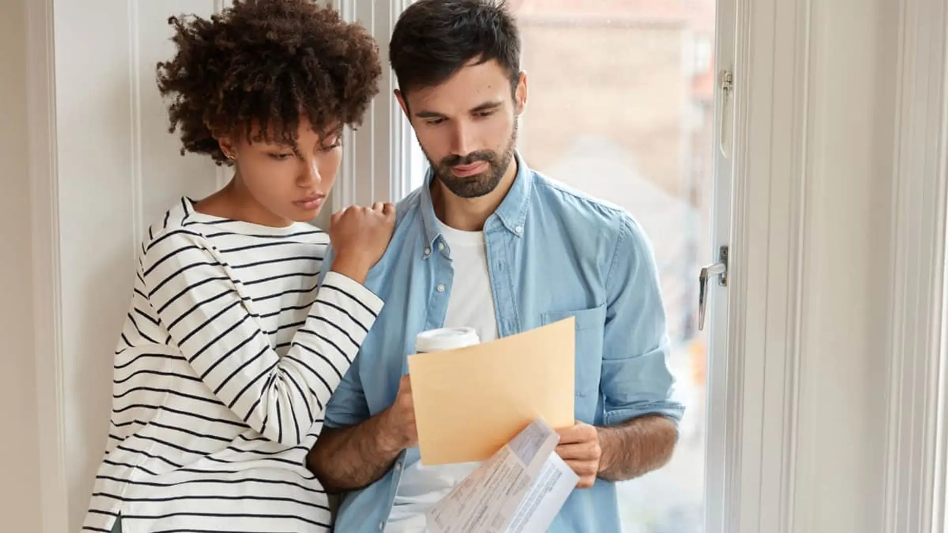 Pareja preocupada revisando documentos financieros juntos, como facturas o un contrato.