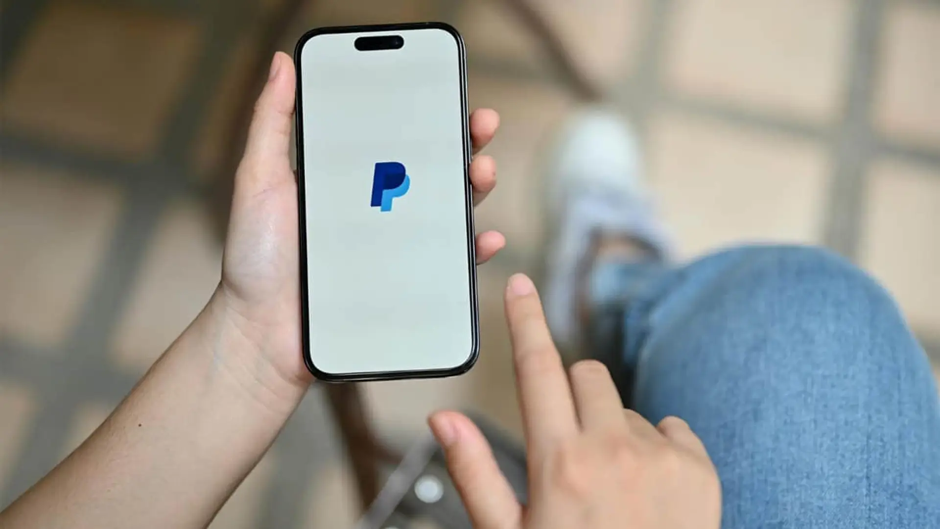 Persona utilizando la aplicación de PayPal en un smartphone para realizar pagos digitales y transacciones.