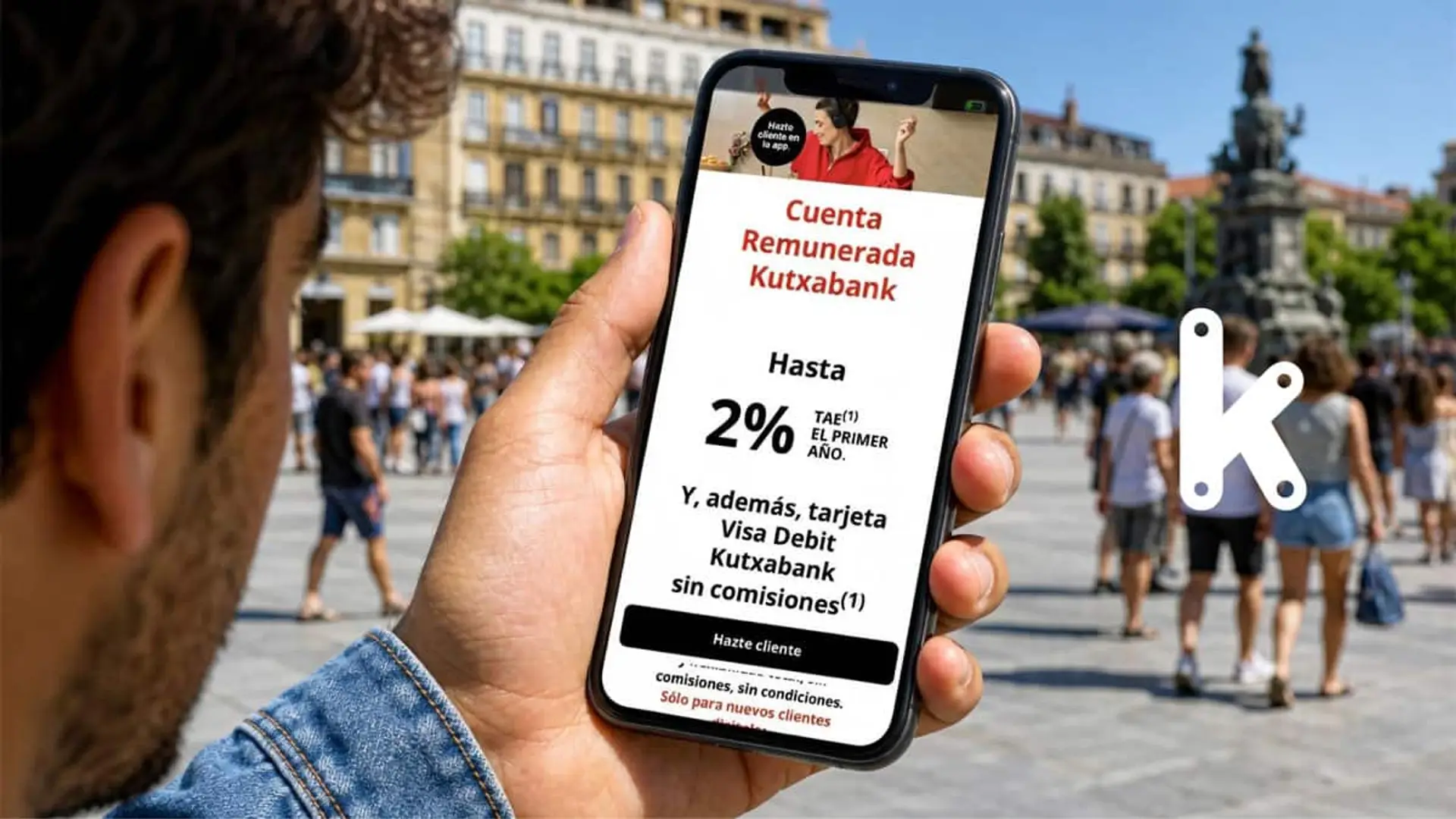 Kutxabank entra en la guerra del ahorro con una cuenta remunerada al 2% TAE: qué ofrece frente a Bankinter y Trade Republic Persona mirando en el móvil una oferta de cuenta remunerada de Kutxabank en una plaza