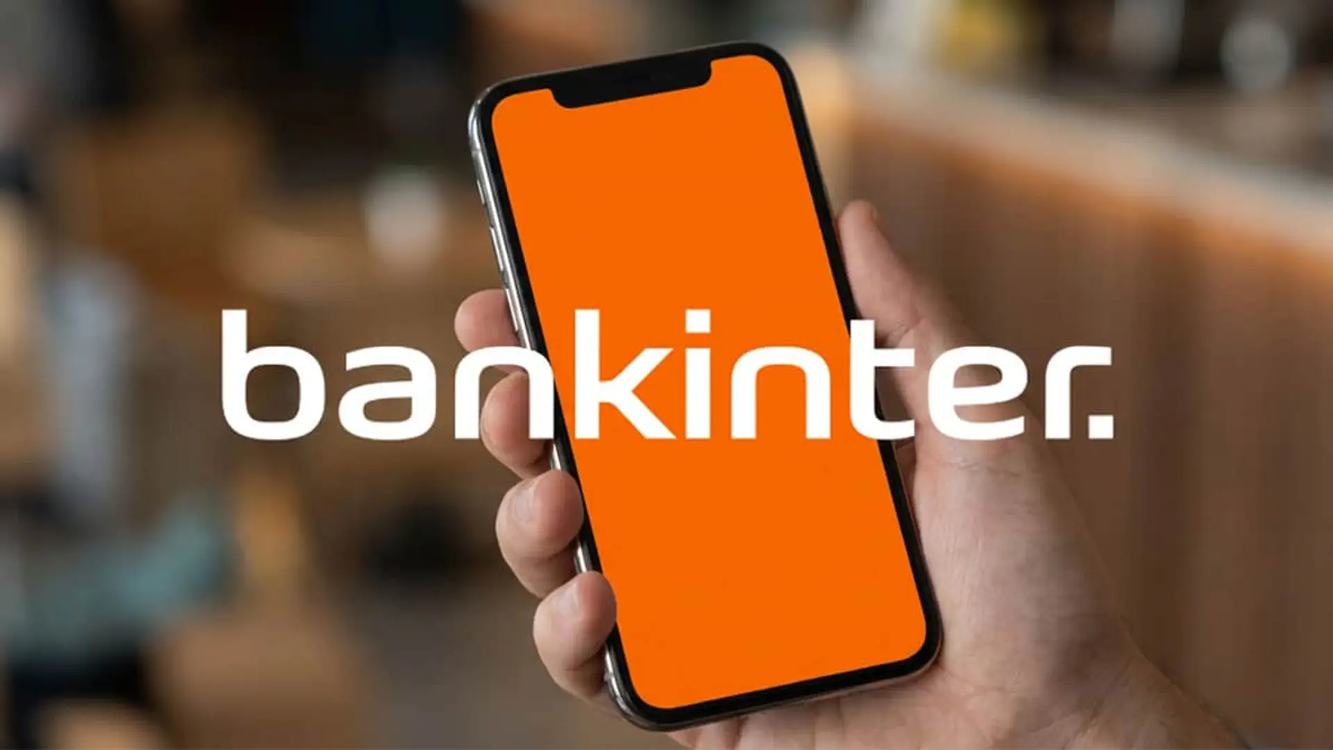 Bankinter mejora la rentabilidad de su cuenta remunerada a más del 2% TAE si cumples este requisito Mano sujetando un smartphone con el logo de Bankinter. App de banca digital para gestionar tus ahorros y finanzas.