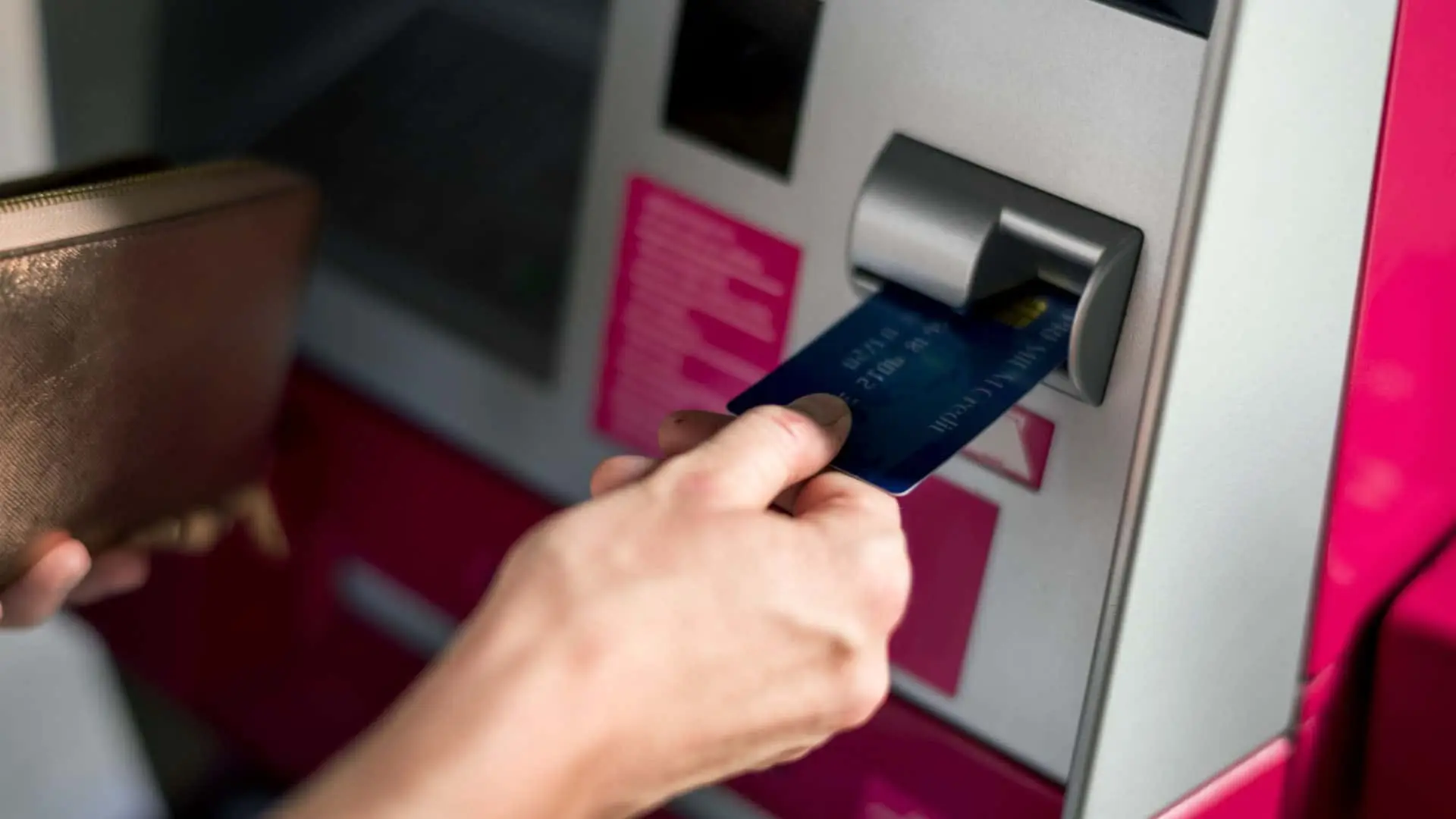 ¿Cuándo se cobra el paro en octubre de 2025? Fechas en Caixabank, Santander, BBVA y otros bancos Persona sacando dinero de un cajero automático (ATM) con su tarjeta de crédito.