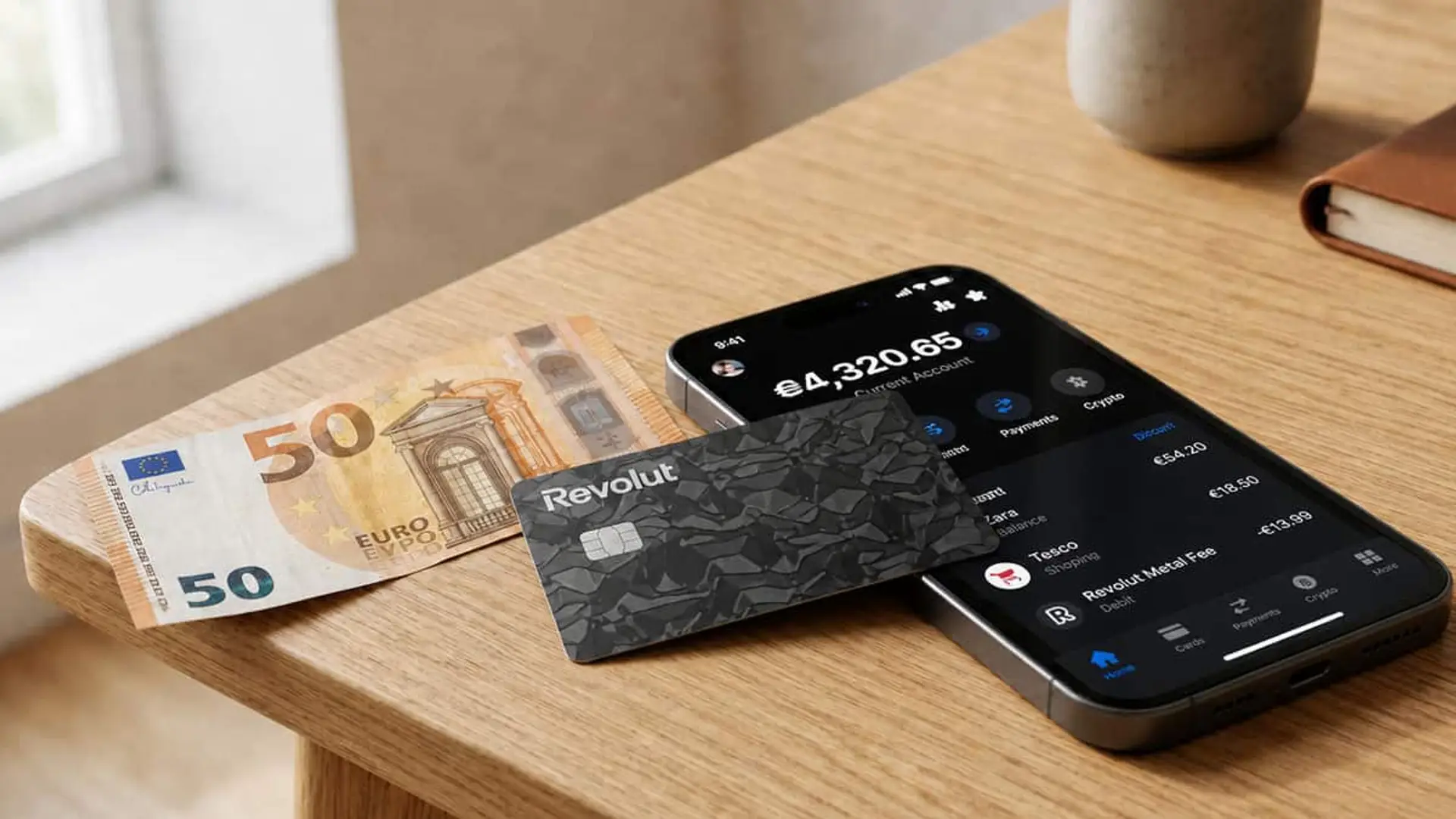 Tarjeta Revolut Metal junto a un móvil con la app de Revolut y un billete de 50 euros