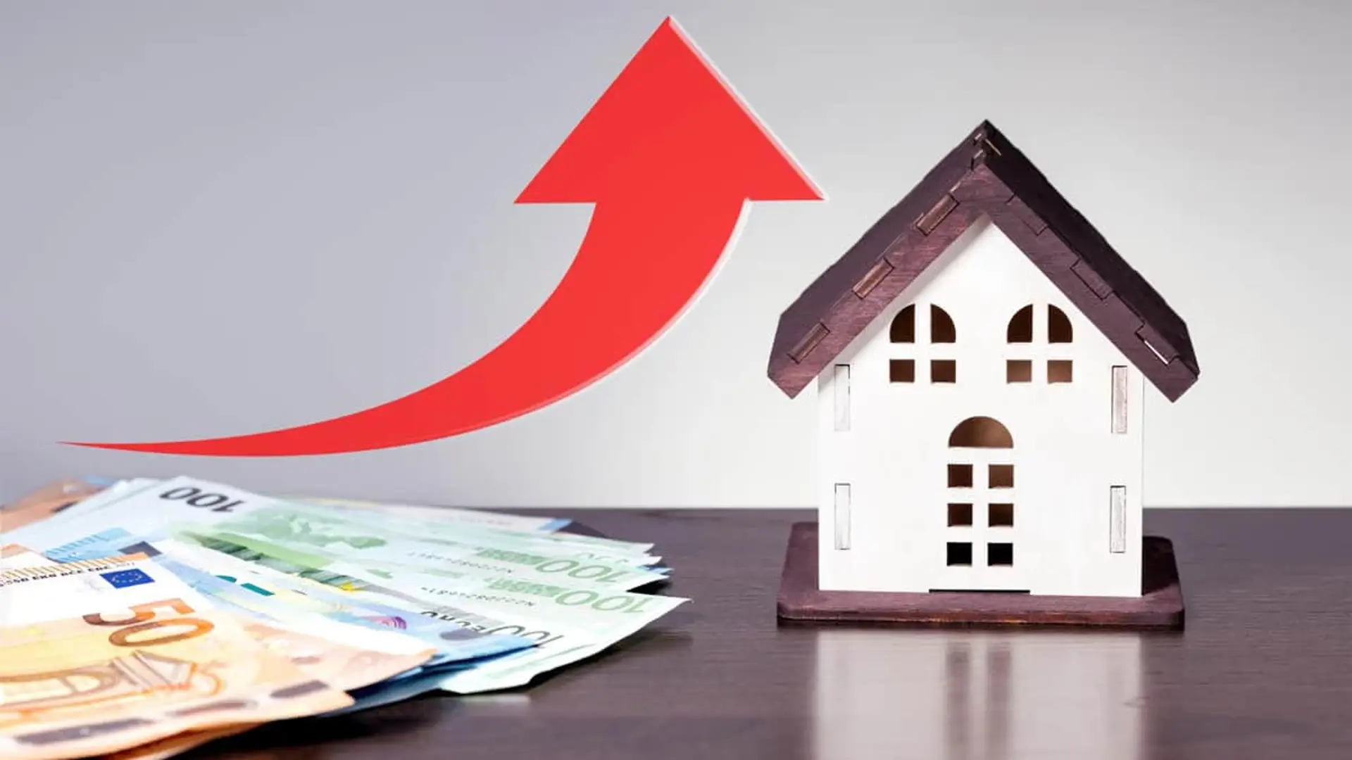 Maqueta de casa y billetes de euro con flecha ascendente, simbolizando la subida del precio de la vivienda o hipotecas.