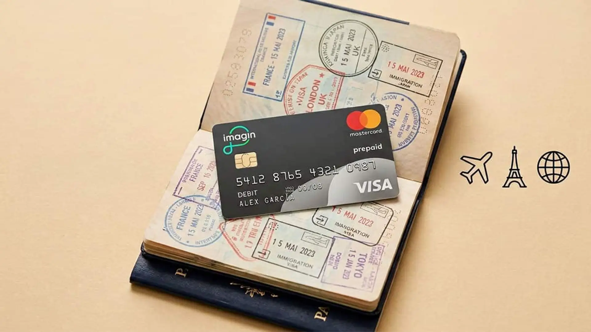 Imagin iguala a Revolut y N26: elimina todas las comisiones en el extranjero sin condiciones Tarjeta de imagin sobre un pasaporte abierto con sellos de viaje y iconos de avión, torre y globo