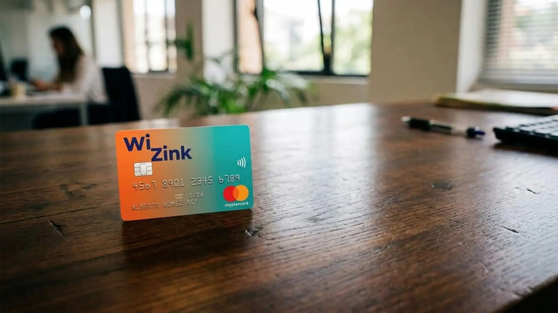 Tarjeta de WiZink colocada sobre una mesa de madera en una oficina con el fondo desenfocado