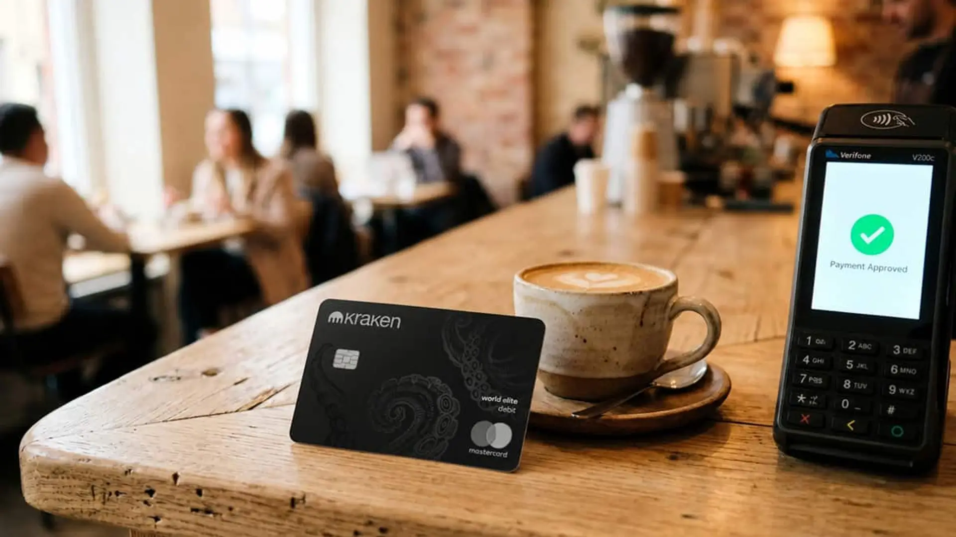 La tarjeta de Kraken llega a España: más de 600 criptos para pagar y cashback de hasta el 2% Tarjeta de Kraken junto a un café y un terminal de pago en una cafetería para pagar con criptomonedas