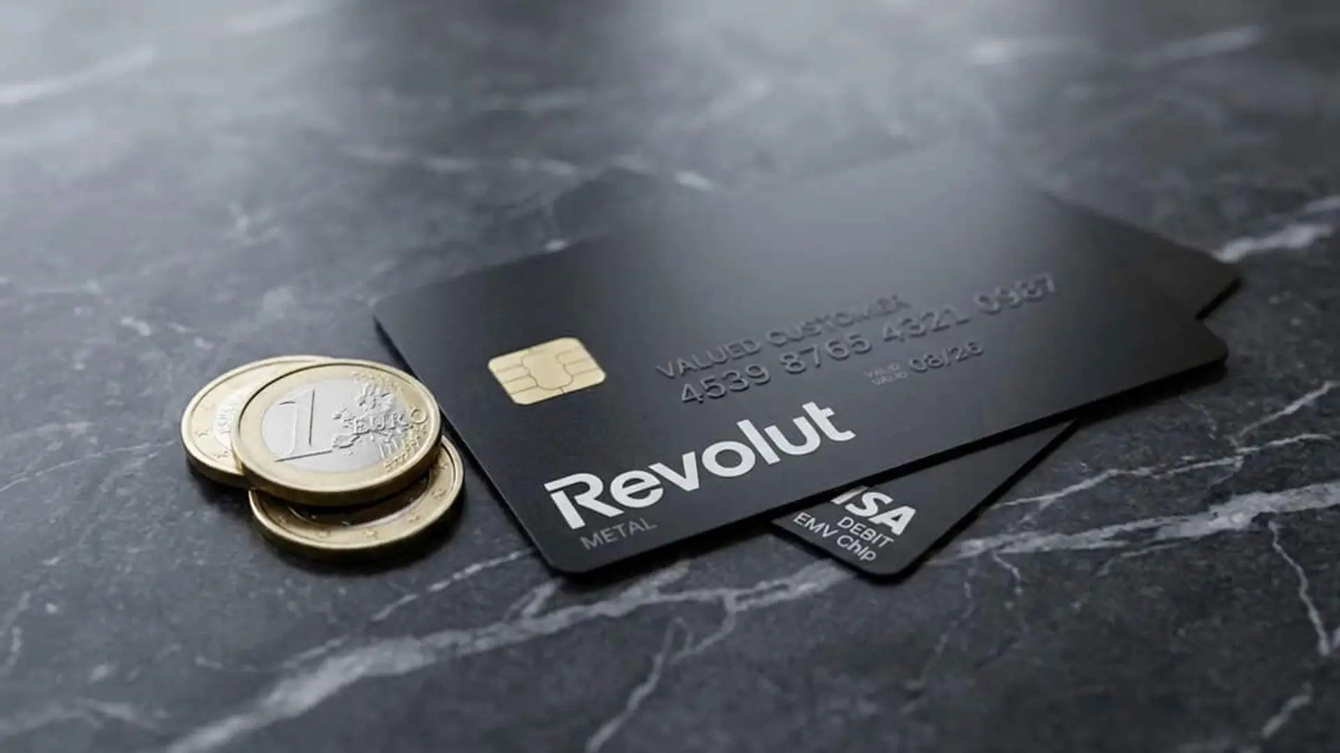 Tarjeta negra de Revolut junto a varias monedas sobre una superficie oscura