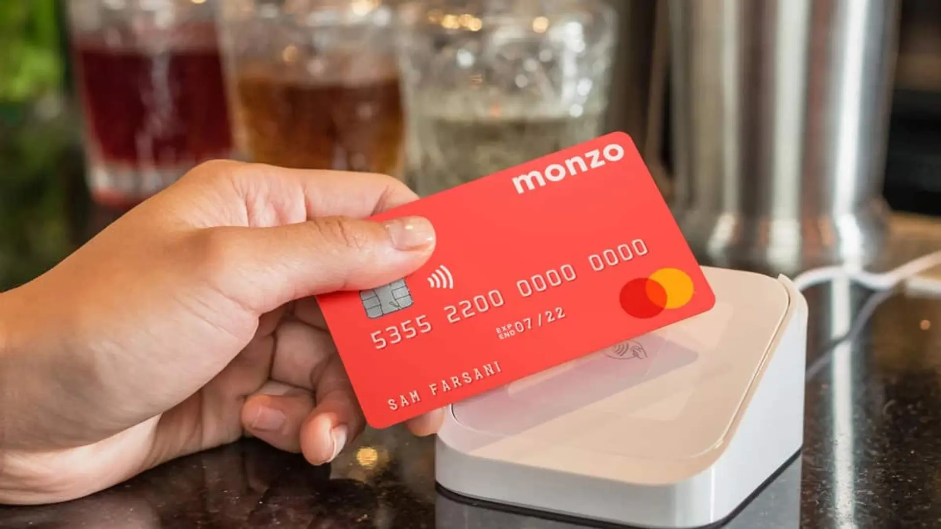 Monzo Bank llegará a España: el gigante neobanco británico ya tiene CEO Mano sosteniendo una tarjeta Monzo rosa realizando un pago sin contacto en un terminal.
