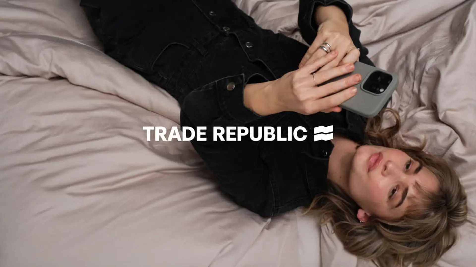 Joven utilizando la aplicación de Trade Republic en su móvil para invertir y gestionar sus ahorros desde casa.