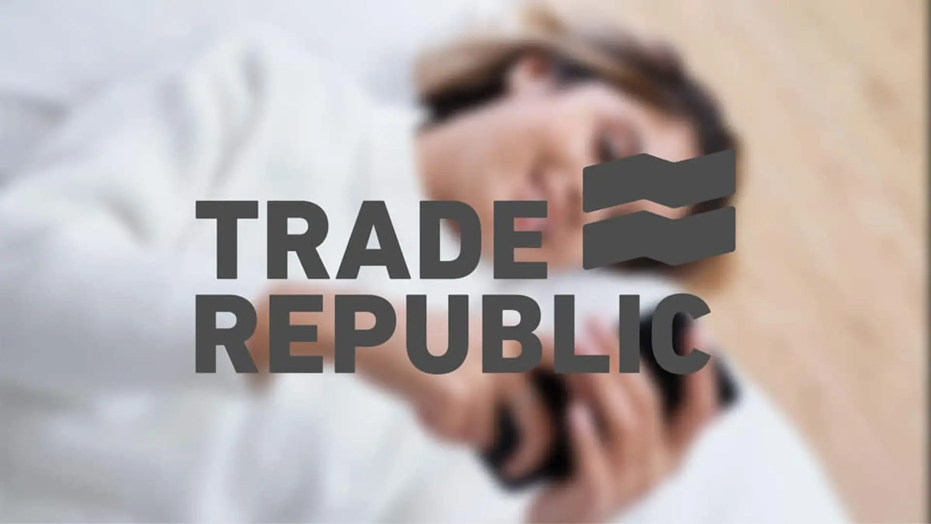 Ni Bankinter ni Sabadell: esta es la cuenta remunerada que mantiene su TAE por encima del 2% Logotipo de Trade Republic sobre fondo desenfocado con persona usando el móvil.