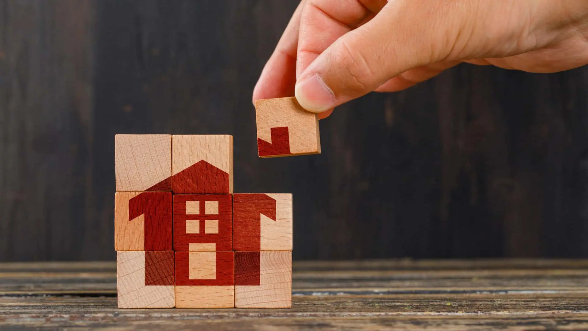 Los 5 motivos por los que el banco puede rechazar tu hipoteca (y cómo evitarlo) Mano construyendo una casa con bloques representa el concepto de la planificación, compra de vivienda, hipoteca o seguro de hogar.