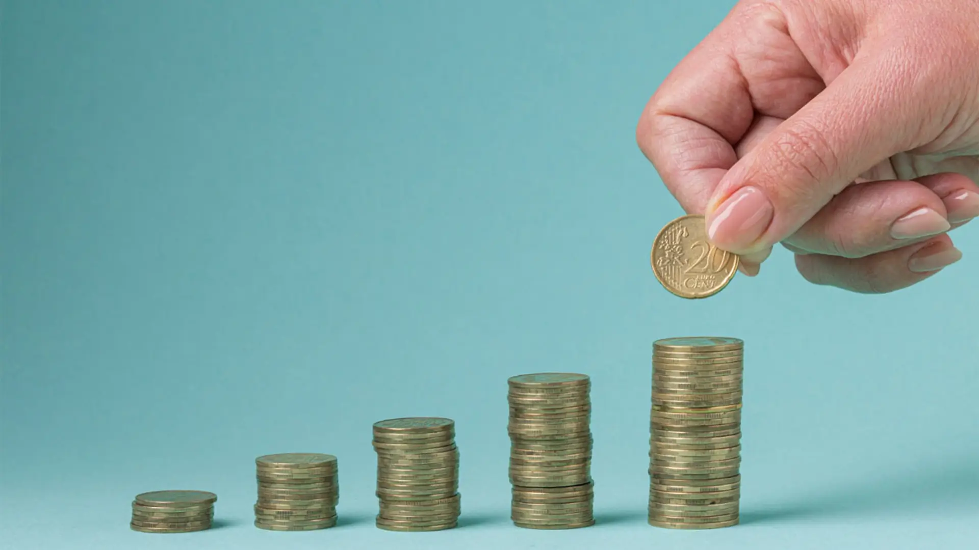 Los 5 errores más comunes al contratar un seguro que afectan a tu ahorro Mano apilando monedas en un gráfico creciente que simboliza el ahorro.