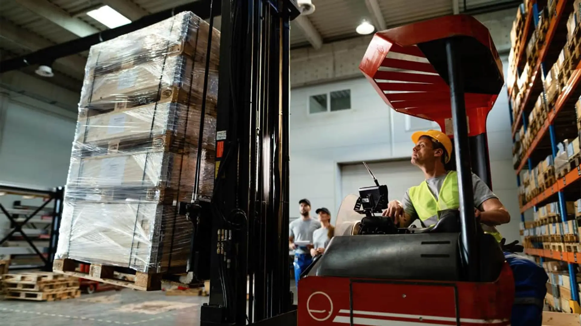 Si tienes una carretilla o un vehículo interno, ojo: podrías enfrentarte a multas muy serias Operario manejando carretilla elevadora para levantar palé con cajas embaladas en almacén logístico.