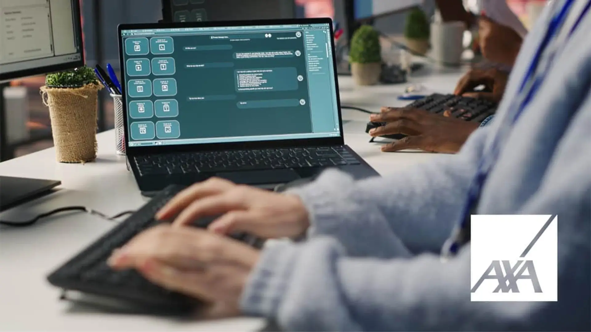 Empleado de AXA trabajando con un ordenador portátil en una oficina de seguros para atención al cliente.