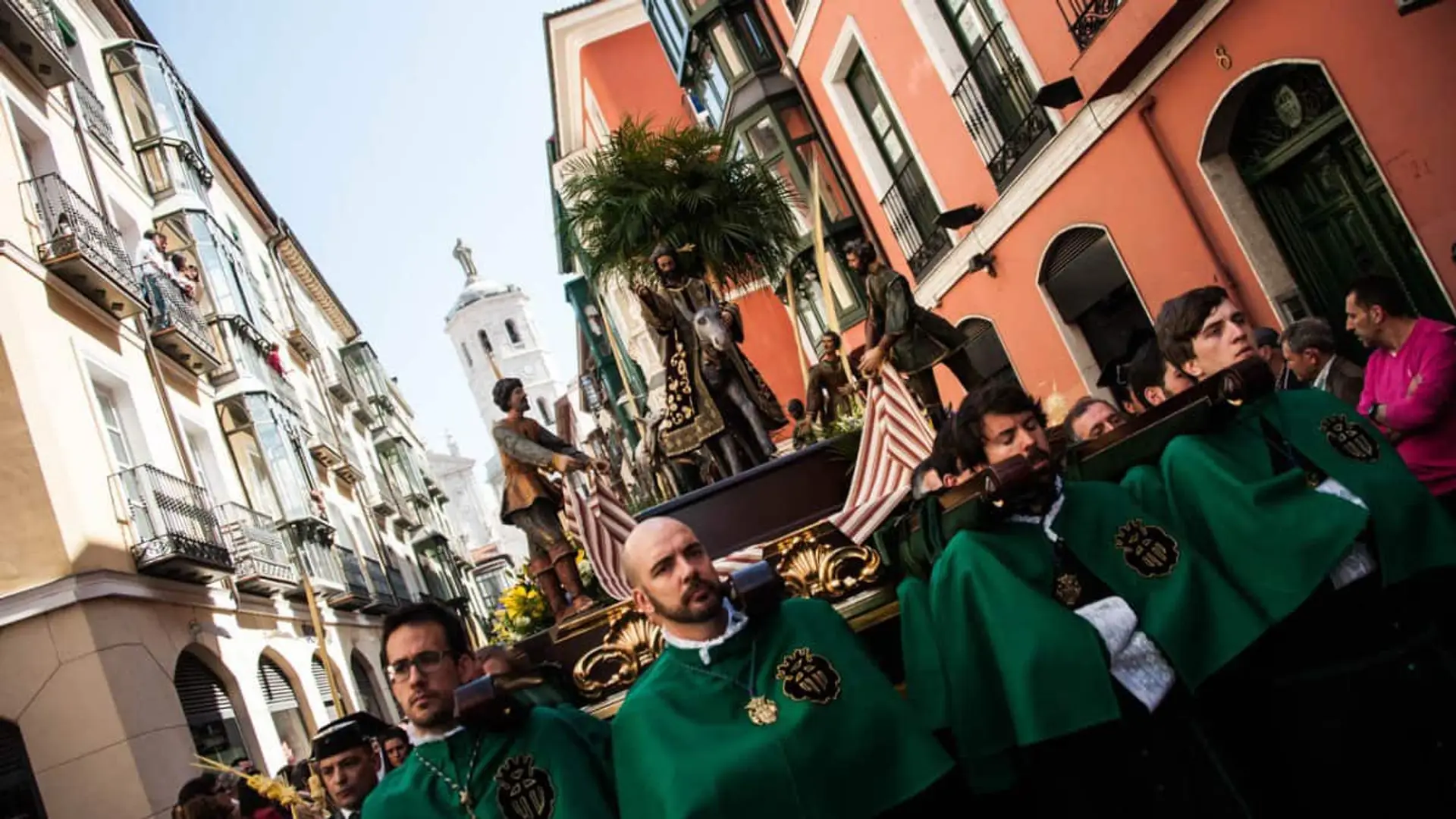Costaleros con túnicas verdes llevando un paso de Semana Santa por una calle de Valladolid.