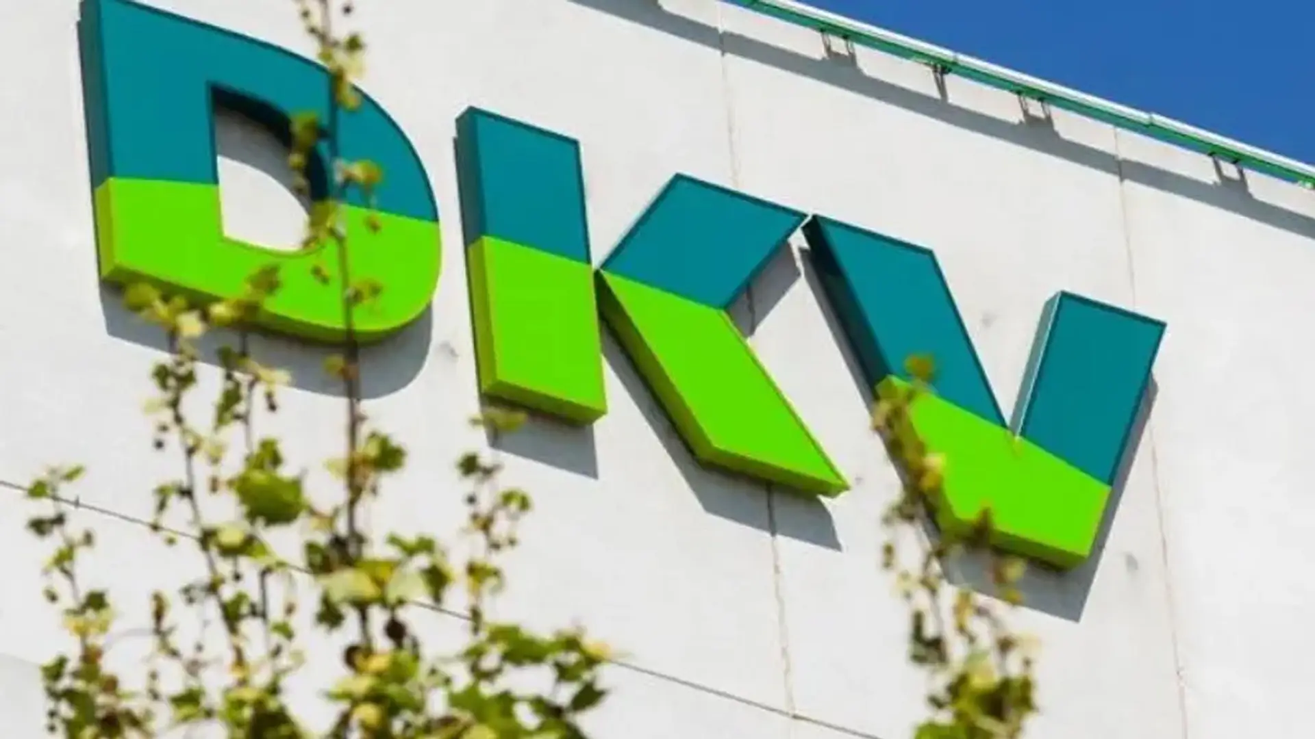 Logotipo de DKV Seguros de salud en la fachada blanca de un edificio corporativo.