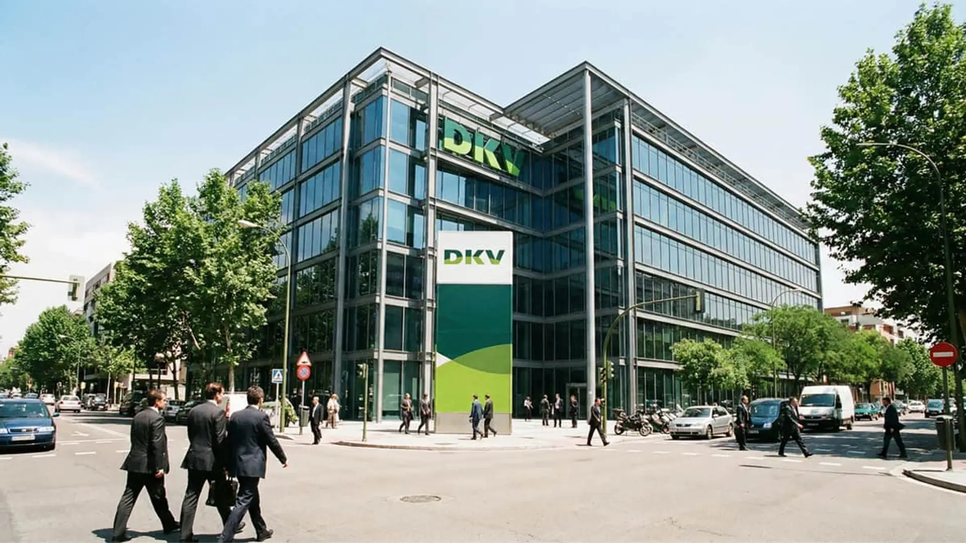 DKV quiere recuperarse tras salir de Muface: así ha reorganizado su cúpula con fichajes en Cigna, Sanitas y Aon Fachada de un edificio de DKV Seguros. Edificio moderno de cristal con personas caminando por la calle