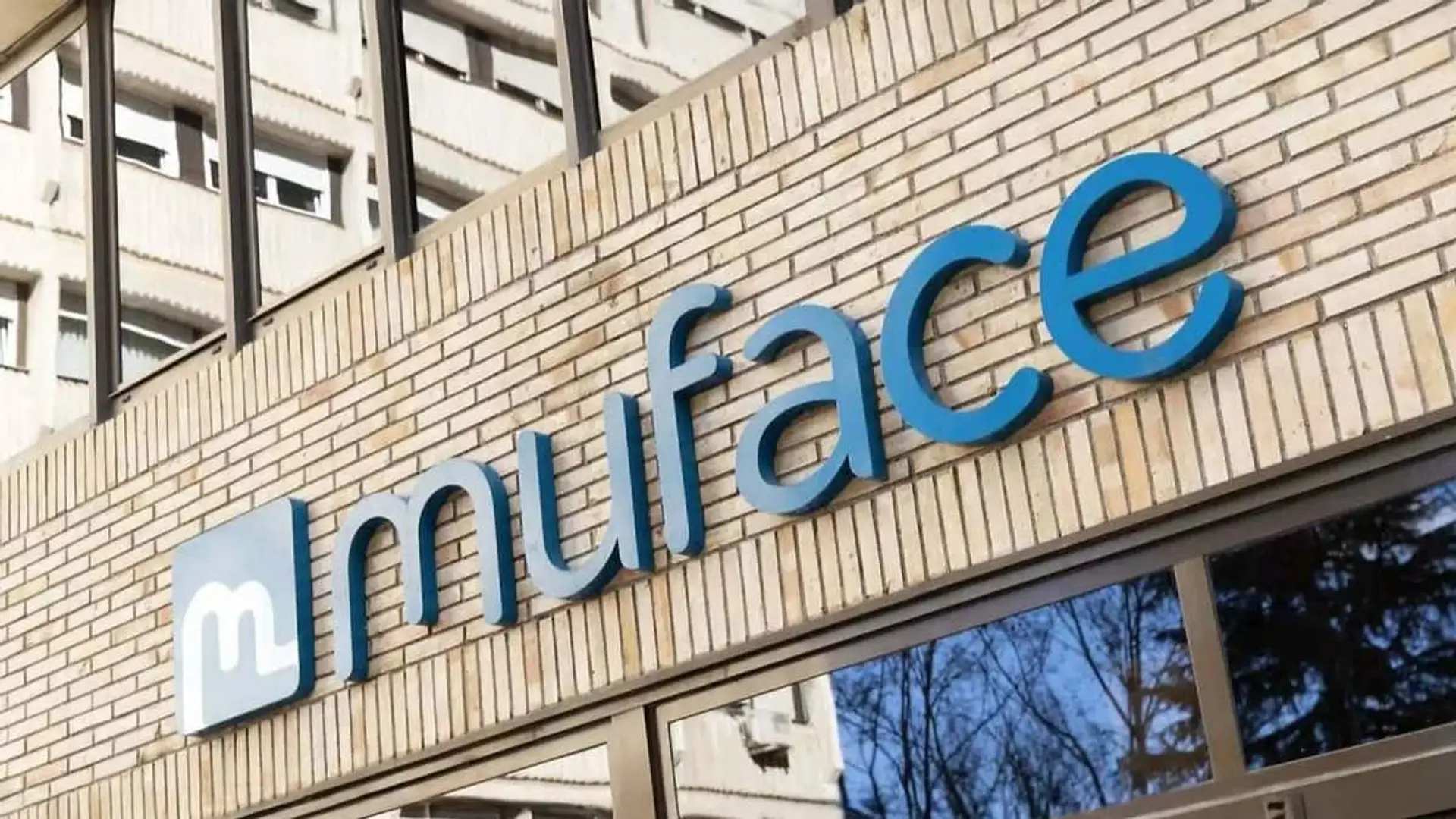 Las primas de Muface aumentan un 26%: Asisa y Adeslas disparan su facturación en seguros de salud Fachada de la sede de Muface con el logotipo visible sobre un muro de ladrillo.