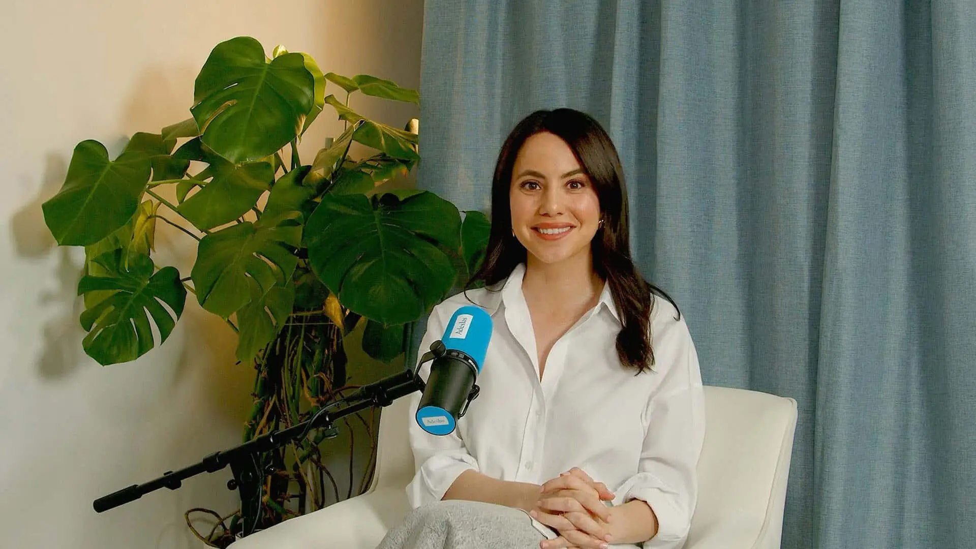 Esther Gómez sonriendo frente a un micrófono durante la grabación del pódcast de Adeslas.