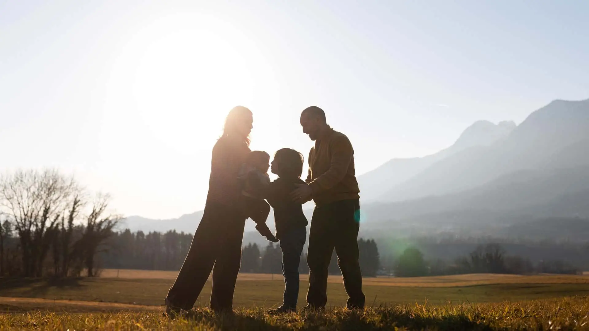 Familia con dos niños disfrutando al aire libre al atardecer en un entorno natural.