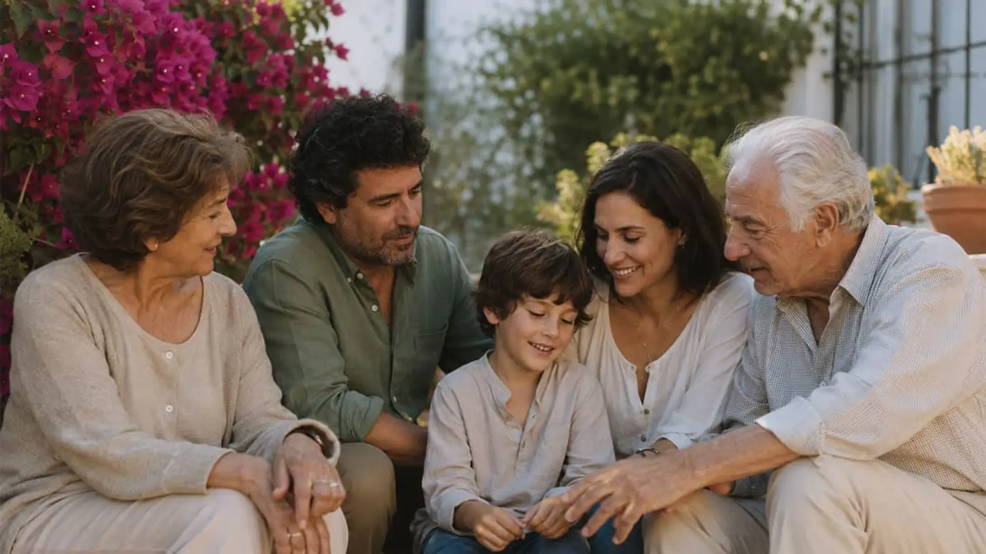 Por qué Active Seguros sigue creciendo sin salirse de los decesos Familia multigeneracional española reunida en terraza exterior con buganvilla rosa al fondo