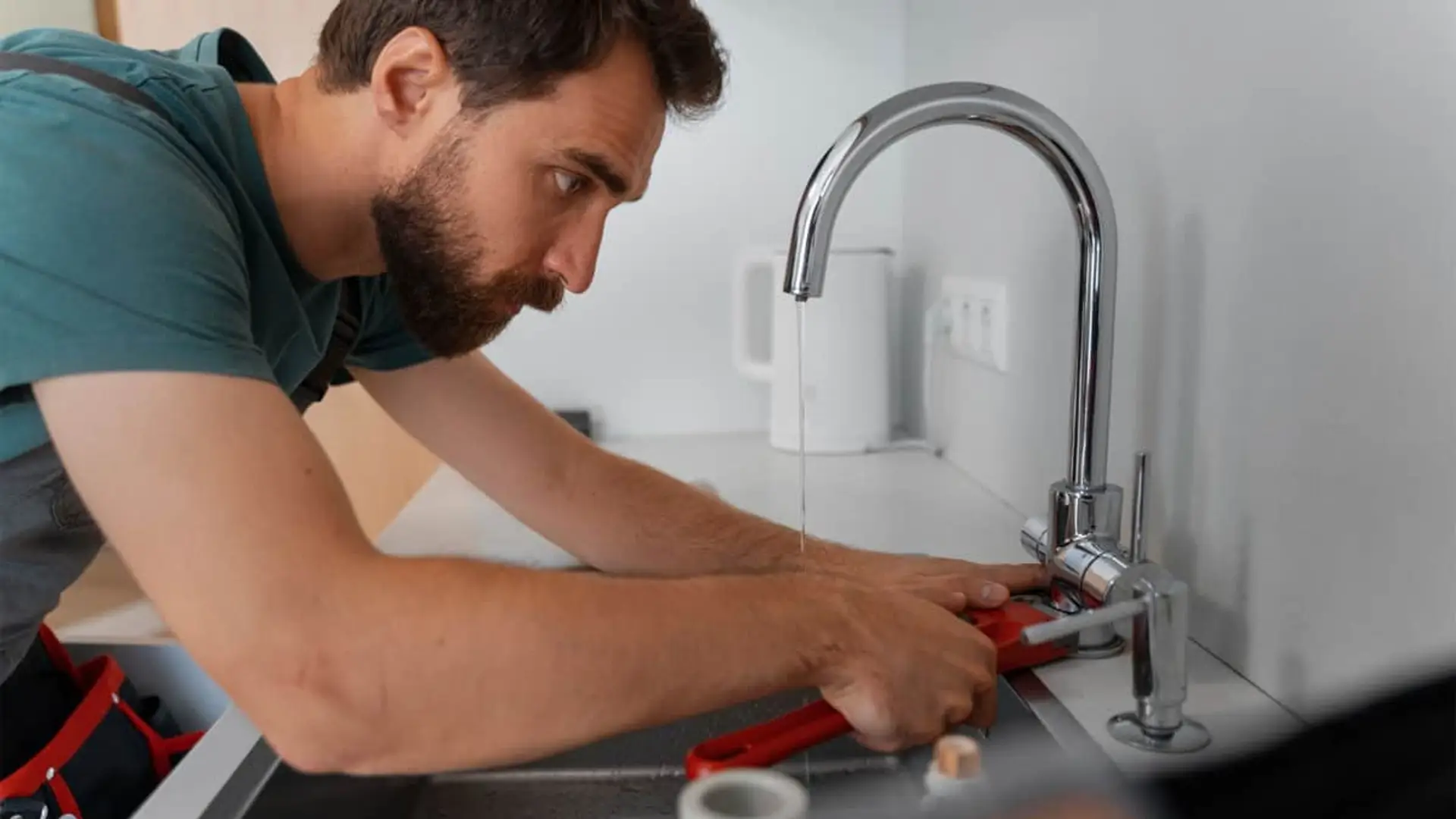 Técnico del servicio manitas realizando una reparación de fontanería en un grifo de cocina.