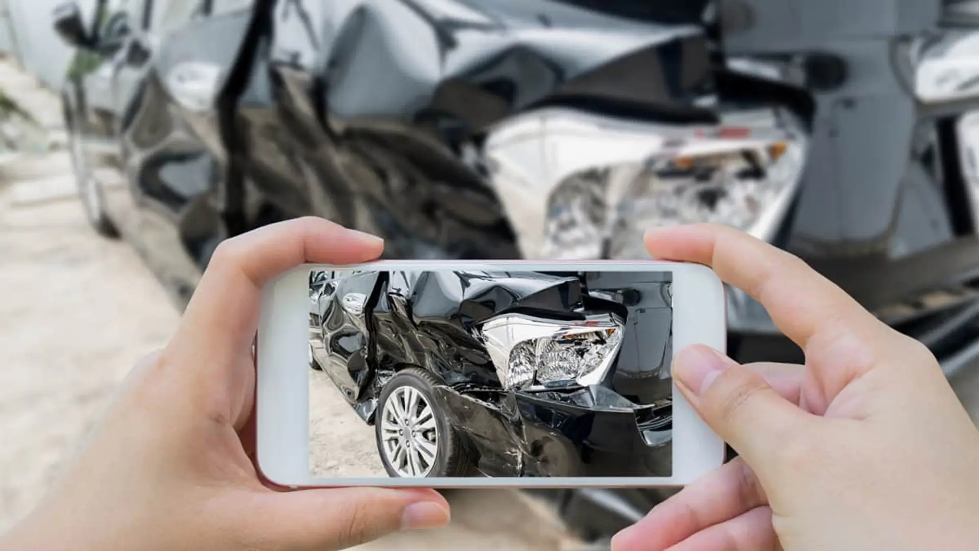 Persona usando su móvil para fotografiar un coche accidentado como parte del proceso de peritación digital del seguro.