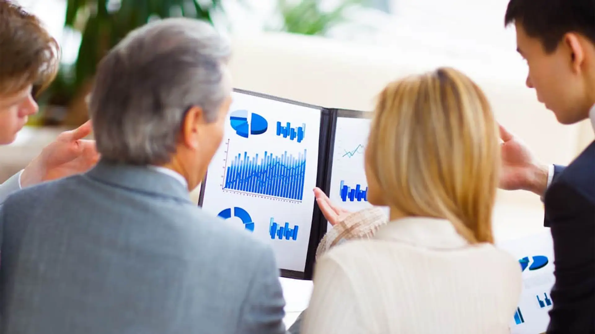 Analistas sector seguros analizando gráficos de rentabilidad e inversión en una reunión de negocios.